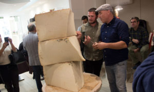 La Majada Quesos celebra su tercer aniversario con la apertura del queso curado más grande del país • El queso, de 174 kilos y elaborado con 1.200 litros de leche, procede de la quesería canaria Bolaños Valencia (26.11.2019). El maestro quesero de la Majada Quesos, Andrés García, y más de una cuarentena de asistentes del mundo quesero han celebrado el tercer aniversario con la apertura del queso curado de leche cruda de cabra más grande de nuestro país. Esta iniciativa partió de La Majada a principios de año, cuando parte del equipo decidió viajar a Las Palmas de Gran Canaria, concretamente a la quesería artesana Bolaños, especializada en maduración de quesos, para elaborar esta joya quesera. Tras casi once meses de maduración, lo alberga el establecimiento valenciano en su cava, y una vez abierto, además de estar a la venta, se distribuirá por porciones a las principales charcuterías y tiendas especializadas en quesos. Al evento han asistido los maestros queseros de la quesería Bolaños Aarón Hérnandez e Isidoro Jiménez; el jefe de servicio de Ganadería del Gobierno Canario, Fernando del Castillo; el presidente de los Queseros Artesanos Valencianos, Ángel Valeriano, además de los representantes de las principales charcuterías del país. La Majada Quesos es una tienda y cheese bar, en los que se pueden degustar, descubrir y comprar los mejores quesos europeos y españoles de pequeños productores artesanos. Para albergar los quesos curados, el espacio cuenta con una cava donde se conservan a una temperatura de entre 12 y 14 grados y una humedad del 80%. También tiene una cava de vinos con más de cien referencias, donde el cliente podrá entrar y elegir el que más le apetezca. Detrás de La Majada Quesos están el experto en quesos Andrés García, jurado de los prestigiosos premios internacionales World Cheese Awards y alma mater de La Despensa de Andrés, una charcutería especializada en quesos artesanos ubicada en el mercado de IBI y que ya es un referente en el sector, y los hermanos Varea, fundadores de Carnes Varea, tiendas especializadas en carnes selectas y productos realizados artesanalmente con más de 25 años de experiencia y que el año pasado recibió la mención de honor en los Premios Nacionales de Comercio Interior. Con este proyecto, sus fundadores pretenden difundir la cultura del queso de autor y el trabajo que realizan las queserías, y ofrecer a sus clientes los mejores productos de elaboradores valencianos, españoles y europeos. También dispone de un espacio reservado para organizar mensualmente catas guiadas de quesos en grupo y su equipo también participa en eventos externos como asesores en la elaboración de mesas de quesos.